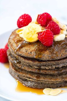 a stack of pancakes topped with bananas and raspberries