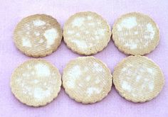 six cookies with white frosting are arranged on a purple surface