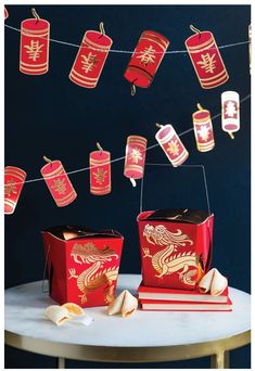 red and gold chinese lanterns hanging from string above table with books on white marble tabletop