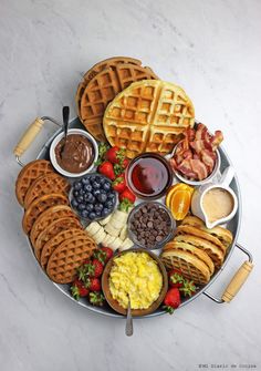 a platter filled with waffles, fruit and other foods