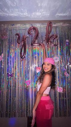 a woman standing in front of a wall with balloons and streamers on it's side