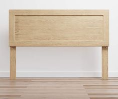 a wooden headboard on top of a hard wood floor next to a white wall