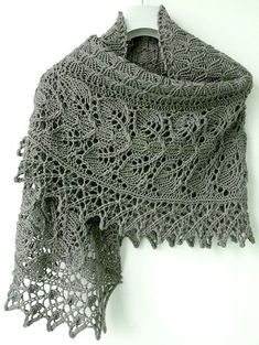 a gray crocheted shawl hanging on a wall