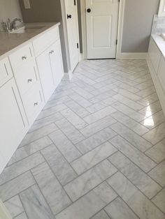 a bathroom with white cabinets and marble flooring