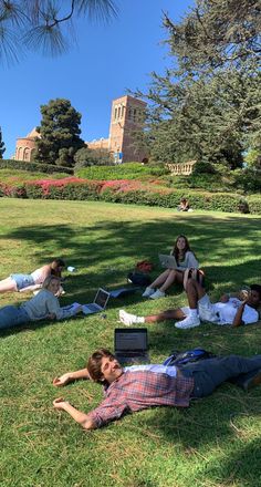 several people laying on the grass with laptops