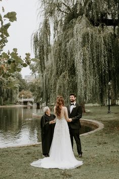 a bride and groom standing next to each other in front of a pond with willow trees