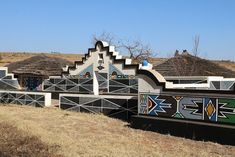 an artisticly designed building in the desert with thatched roof tops and grass roofs