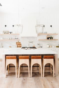 a kitchen with white walls and wooden flooring next to an island in the middle