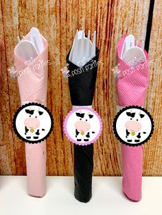 three pink and black umbrellas with stickers on them, one has a cow