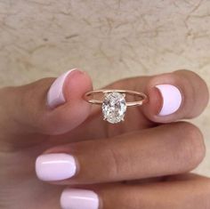 a woman's hand holding a ring with a diamond on it