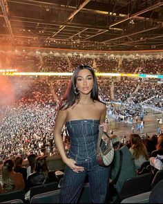 a woman standing in front of an audience at a basketball game with her hand on her hip