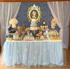 a table topped with lots of cake and desserts next to a curtained window