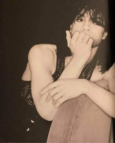 a black and white photo of a woman with her hand on her face while sitting down