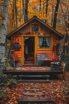 a small wooden cabin in the woods surrounded by fall leaves and trees with colorful decorations