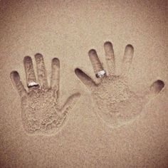 two hand prints in the sand, one has a ring on it