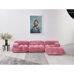 a pink couch sitting on top of a rug in a living room next to a painting