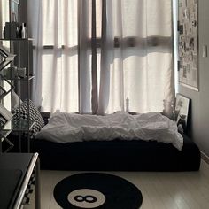 a black and white bedroom with a round rug in front of the window that has curtains on it