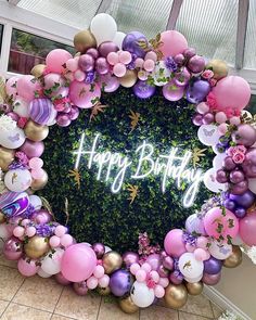 a happy birthday sign surrounded by balloons and flowers