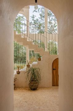 an archway leading to the upper level of a house with potted plants on either side