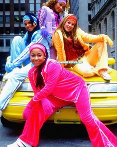 the girls are posing on top of a yellow car