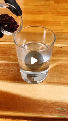 someone is pouring water into a glass with blackberries in it on a wooden table