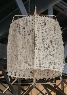 a lamp hanging from the ceiling in a room with wooden beams and metal bars around it