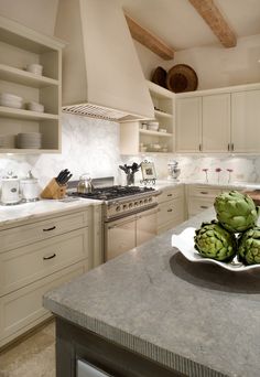 a plate with some artichokes on it sitting on a counter in a kitchen