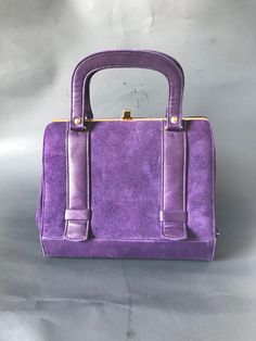 "This is an elegant 50s art deco, Kelly style structured handbag in deep purple suede and leather. It is a Kelly frame bag dating to the 50s. This beautiful handbag's interior features black faux leather interior with one zippered pocket and one slip pocket with gold piping. Kiss-lock closure. In excellent vintage condition considering age and use. Approximate measurements - 7\" high x 8 1/4\" wide and 4\" in depth. The strap drop is 3\". Marked Made in Canada. Prices are listed for Canada and U Classic Purple Evening Bag, Evening Purple Shoulder Bag With Top Carry Handle, Retro Evening Satchel With Hasp Closure, Classic Purple Rectangular Bag, Purple Top Handle Bag For Formal Occasions, Formal Purple Top Handle Bag, Elegant Purple Rectangular Satchel, Classic Purple Rectangular Satchel, Retro Purple Bags For Daily Use