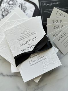 the wedding stationery is laid out on top of each other, with black ribbon