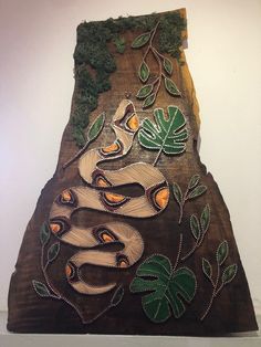 a wooden sculpture with an image of a snake on it's face and leaves