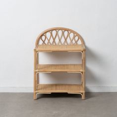 a wicker shelf sitting on top of a cement floor next to a white wall