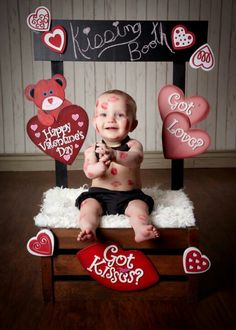 a baby is sitting on a chair with hearts and teddy bears in front of him