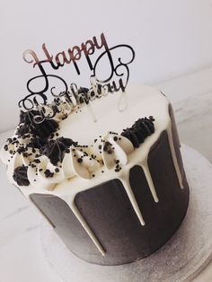 a birthday cake with white frosting and black sprinkles