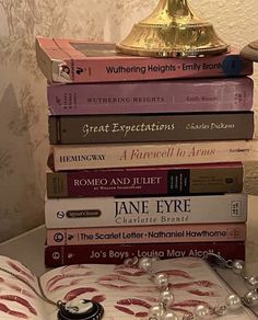 a stack of books sitting on top of a table next to a lamp and other items