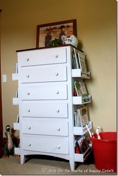 there is a white dresser with many books on it