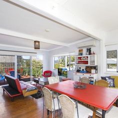 a living room filled with furniture and a red table in front of a large window