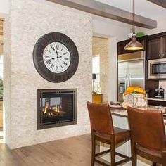 a kitchen with a large clock mounted to the wall next to a dining room table