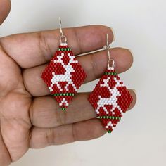 a pair of red and white beaded earrings in the shape of an ornament