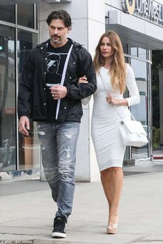 the man and woman are walking down the street together, one is carrying a handbag