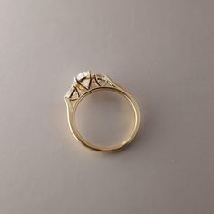 a yellow gold ring with three diamonds on the top and bottom, sitting on a gray surface