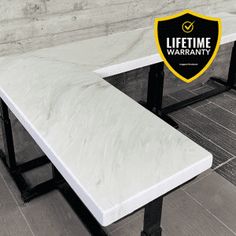 a white marble bench sitting on top of a tile floor next to a black metal frame