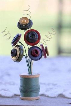 a vase filled with buttons and thread on top of a table