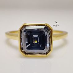 a blue and white diamond ring sitting on top of a white surface with an inscription above it