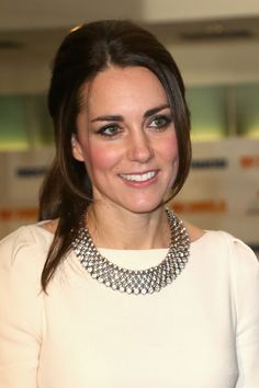 a woman wearing a white dress with a necklace on her neck and smiling at the camera