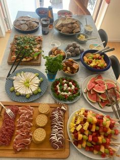 an assortment of food is displayed on a long table with utensils and plates