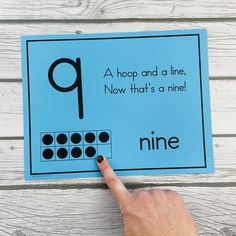 a hand pointing at a blue paper with black dots on it that says nine, hop and a line now that's a nine