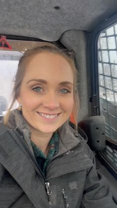 a woman sitting in the back seat of a car smiling at the camera with her eyes closed