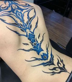 the back of a woman's body with blue tattoos on her lower and upper half