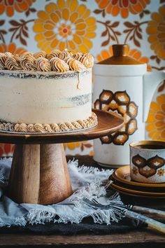 a cake sitting on top of a wooden table next to a cup and saucer