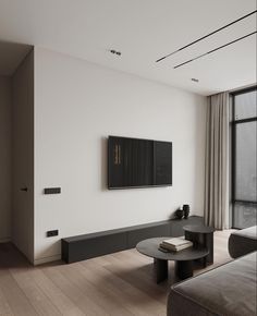 a living room with a couch, table and television on the wall in front of large windows